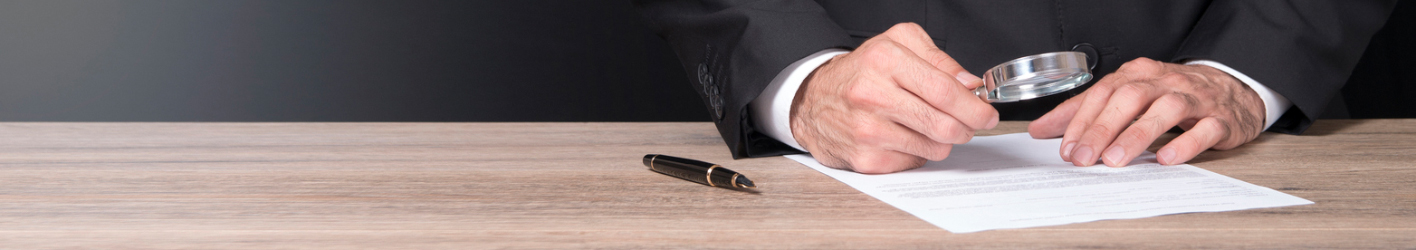 Man looking at legal document with magnifying glass