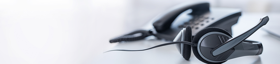 Picture of a desk phone with a headphone set nearby