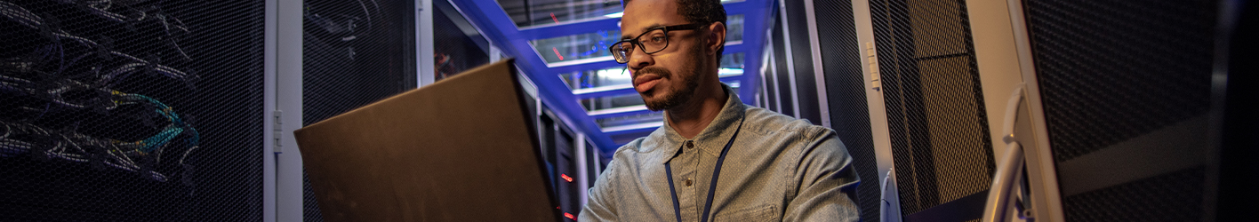 Man working on a laptop in a server room