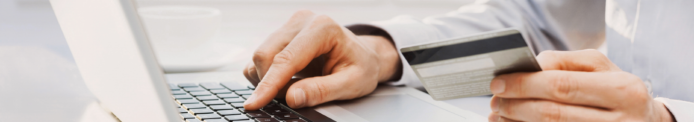 Person looking at credit card an inputting the information into his laptop