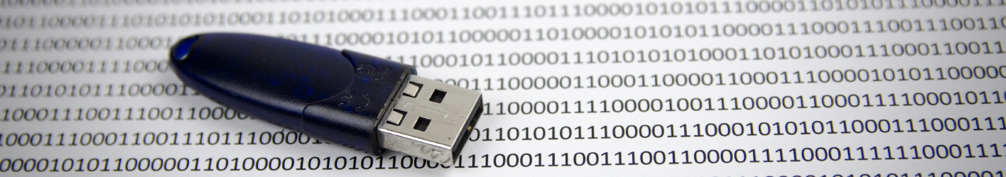 A USB key on top of a paper that has a lot of ones and zeros