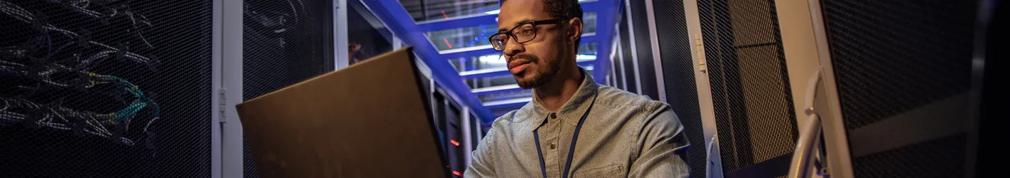 Man working on a laptop in a server room