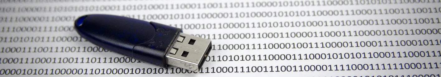 A USB key on top of a paper that has a lot of ones and zeros