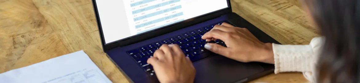 person working on a computer with a paper to the side