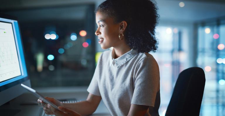 Woman looking at computer holding a tablet