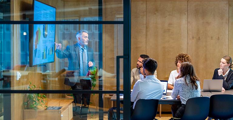 Man presents a slide deck to a board meeting