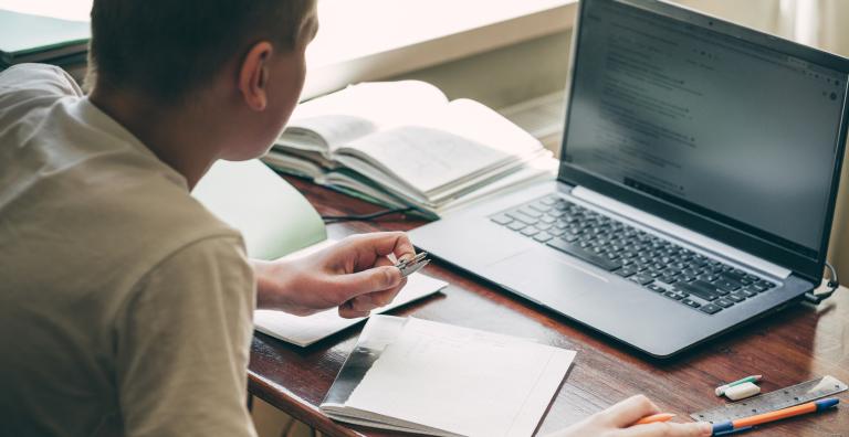 Man studies laptop screen at a desk